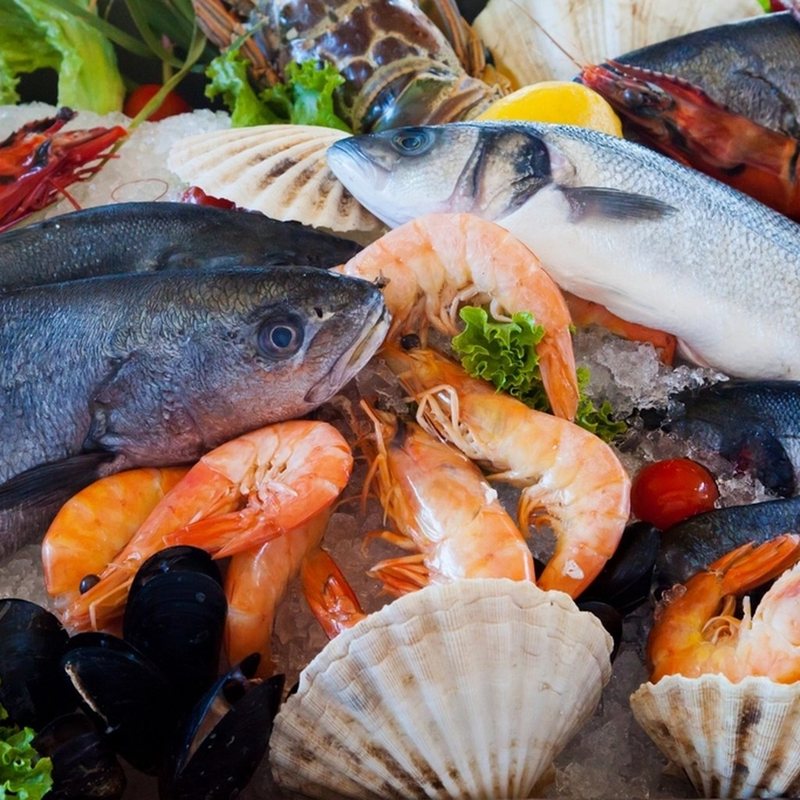 Ikan segar di atas es dan potongan daging di talenan